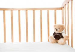 leeres Kinderbett mit Teddy